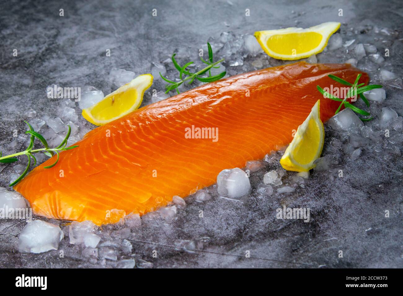 Steak de saumon frais cru avec épices sur glace sur fond de pierre sombre. Aménagement créatif en poisson, vue de dessus, plat Banque D'Images