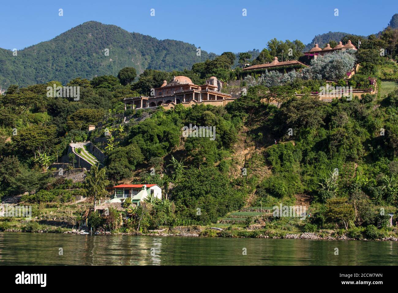 Villa spacieuse sur la rive du lac Atitlan, Guatemala avec une colline abrupte et boisée derrière et un lac en premier plan. Banque D'Images