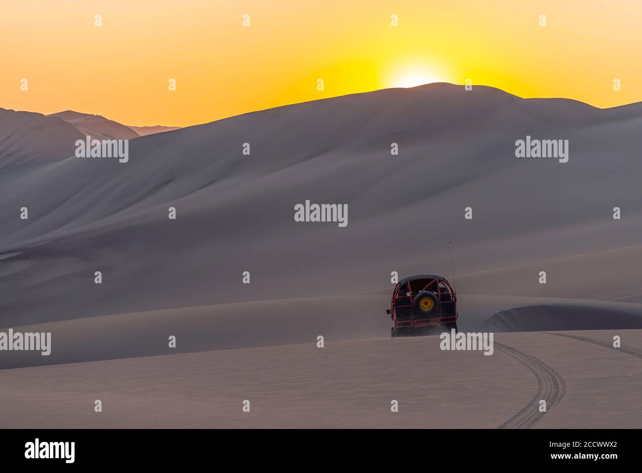 Silhouette d'un buggy volant dans le désert péruvien côtier au coucher du soleil entre ICA et Huacachina, Pérou. Banque D'Images