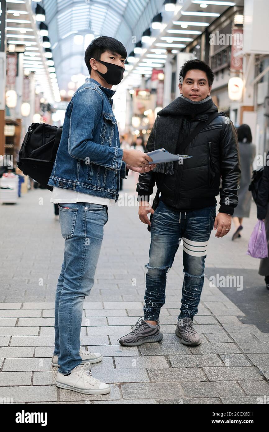 Deux jeunes hommes asiatiques ouvrent la carte pour voyager avec ami et à la recherche d'un restaurant sur le marché Banque D'Images