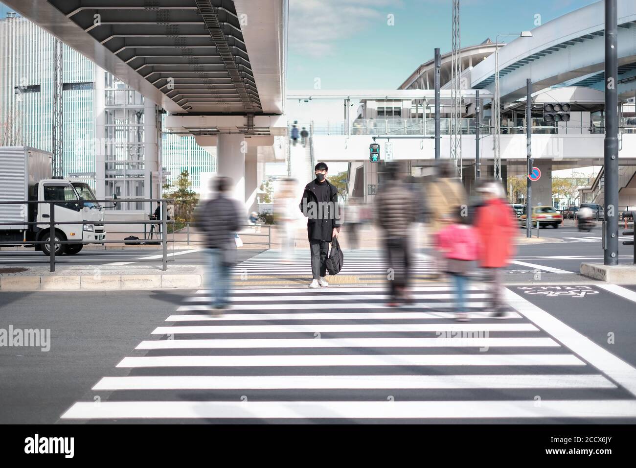 Le jeune homme porte un masque noir et attend de se croiser route sous le pont en béton près de la gare électrique Banque D'Images