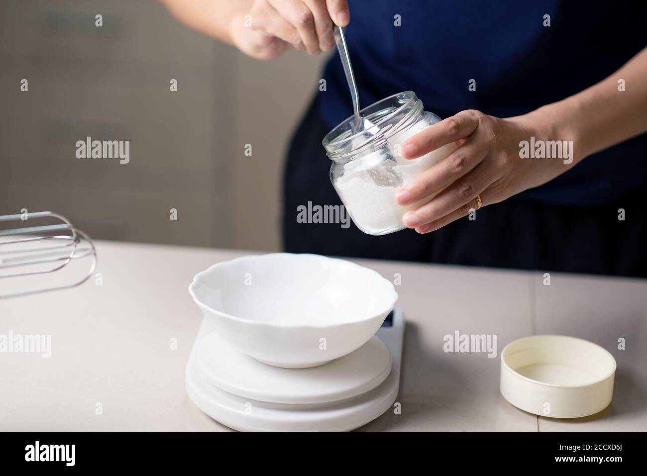 Femme mesurant des ingrédients de cuisine sur une petite échelle de cuisine pendant faire des biscuits dans la cuisine à la maison de près Banque D'Images