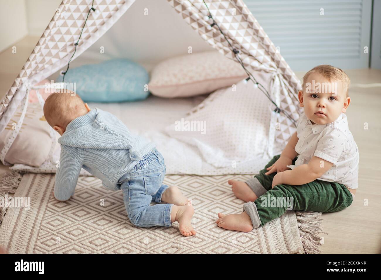 Couple de petits garçons de 1 an jouant seuls dans une tente jouet avec guirlande à la garderie à l'intérieur de la maison. Banque D'Images