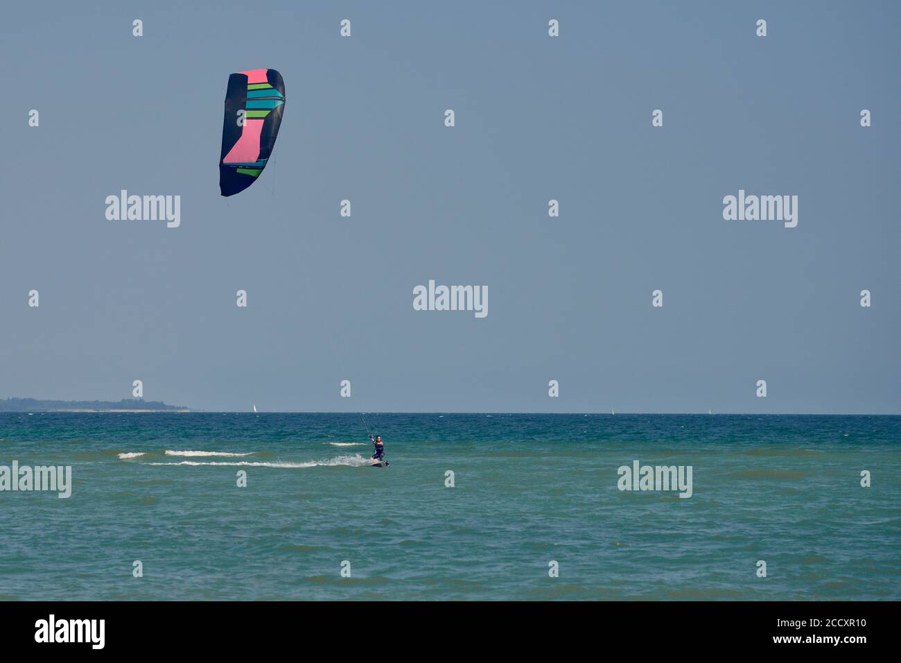 Brunette femme kitesurf ou kite embarquement vers la caméra sur une journée d'été ensoleillée avec vue sur le appareil photo Banque D'Images