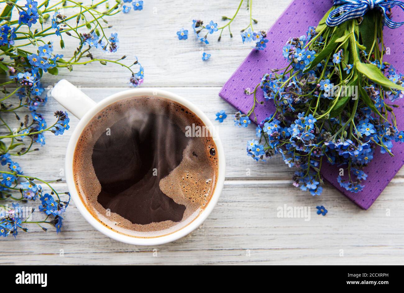 Fleurs bleues oubliées, carnet et une tasse de café chaud. Le concept de vacances et de bons voeux du matin. Banque D'Images