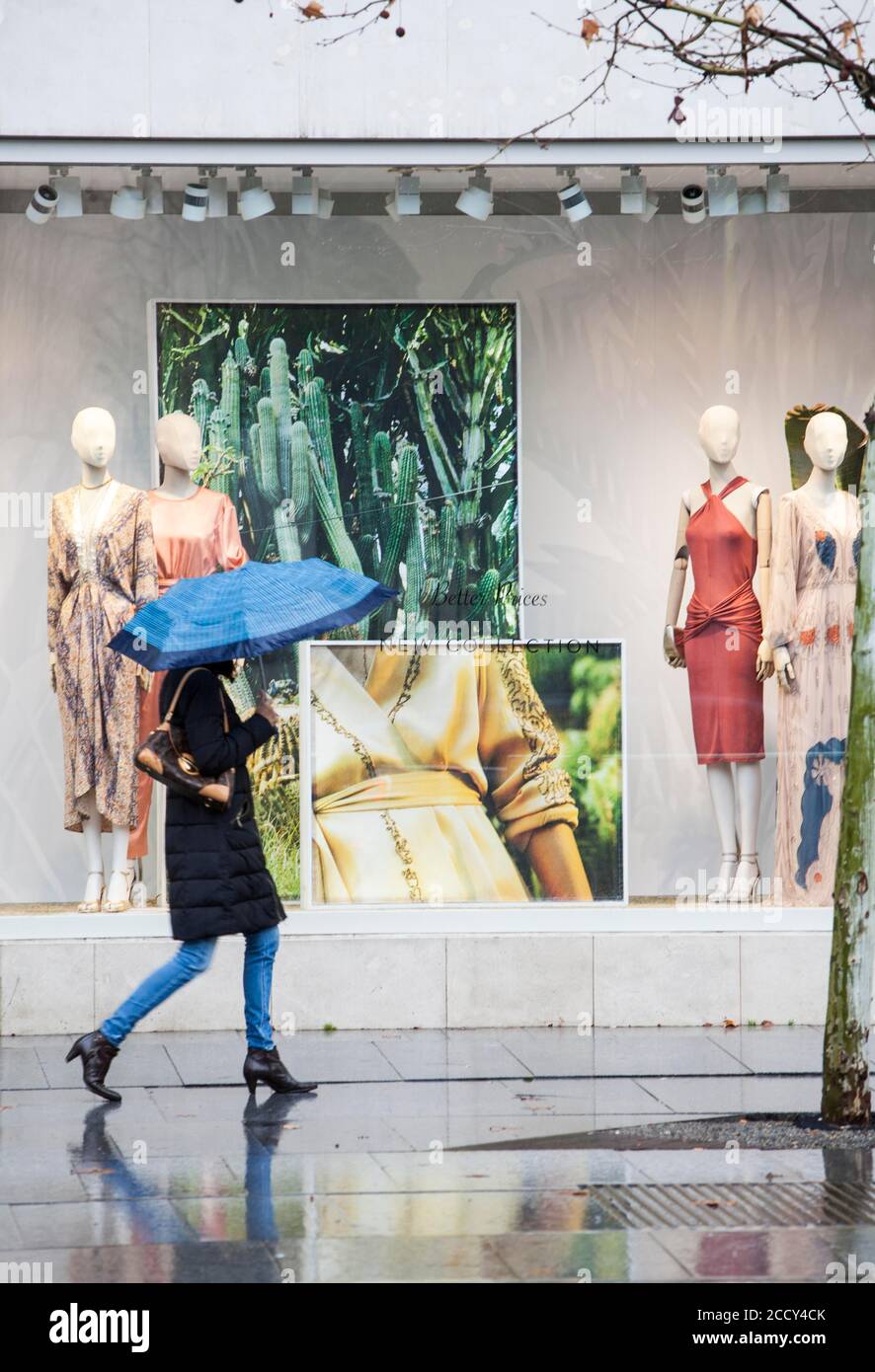 Une femme avec un parapluie bleu descend la rue serrano, l'une des plus visitées et pleine de boutiques de mode, Madrid Banque D'Images