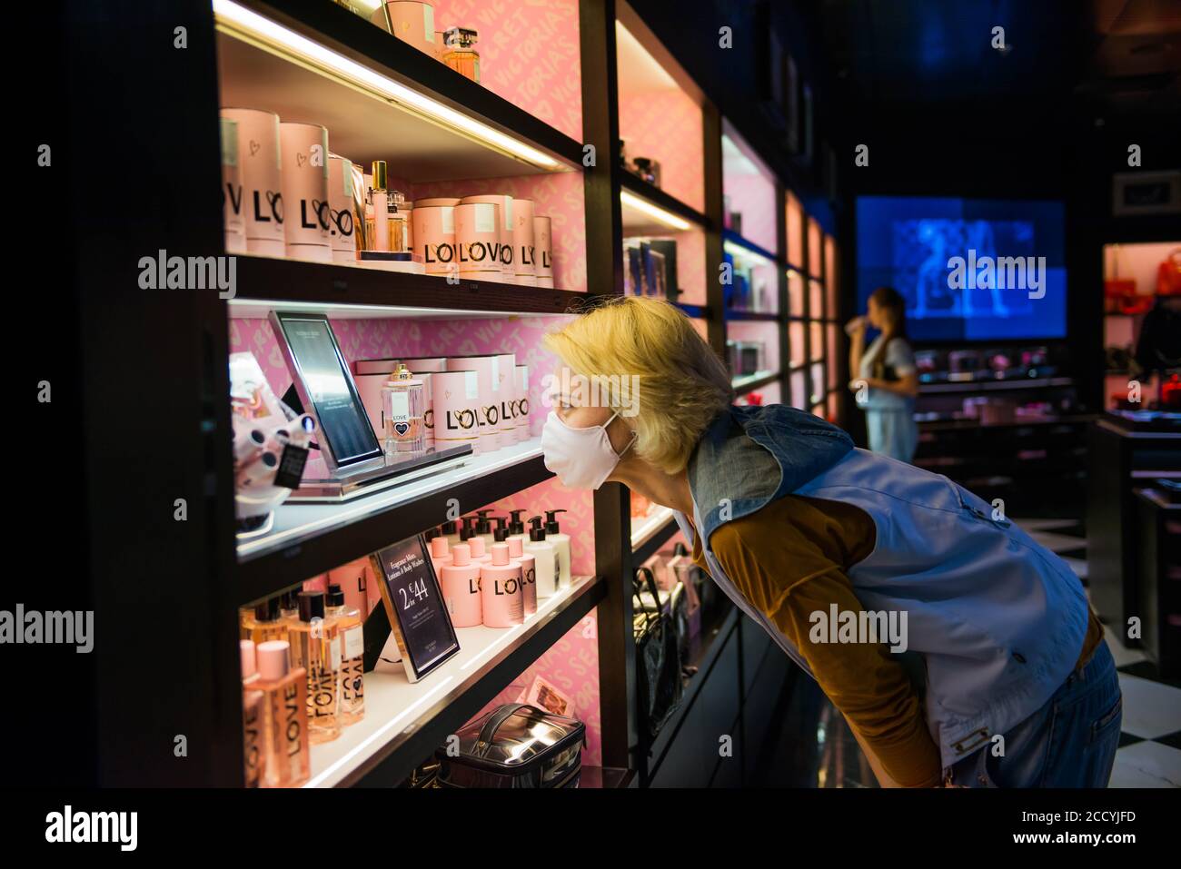 touristes femme dans le masque de protection regardant l'étagère avec célèbre marques en boutique hors taxes Banque D'Images
