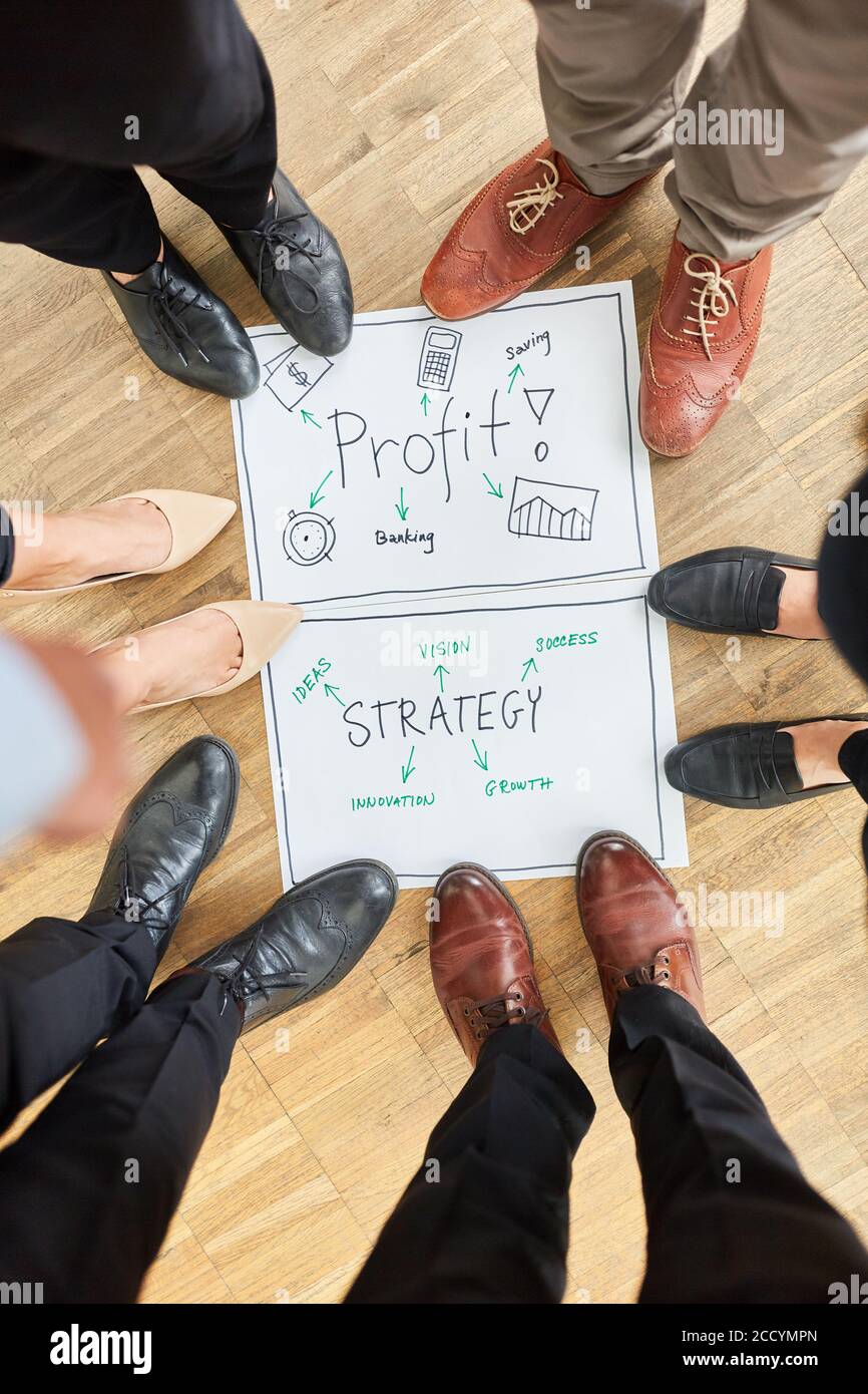 Groupe de gens d'affaires debout dans un cercle autour de mots stratégie et profit sur le plancher Banque D'Images