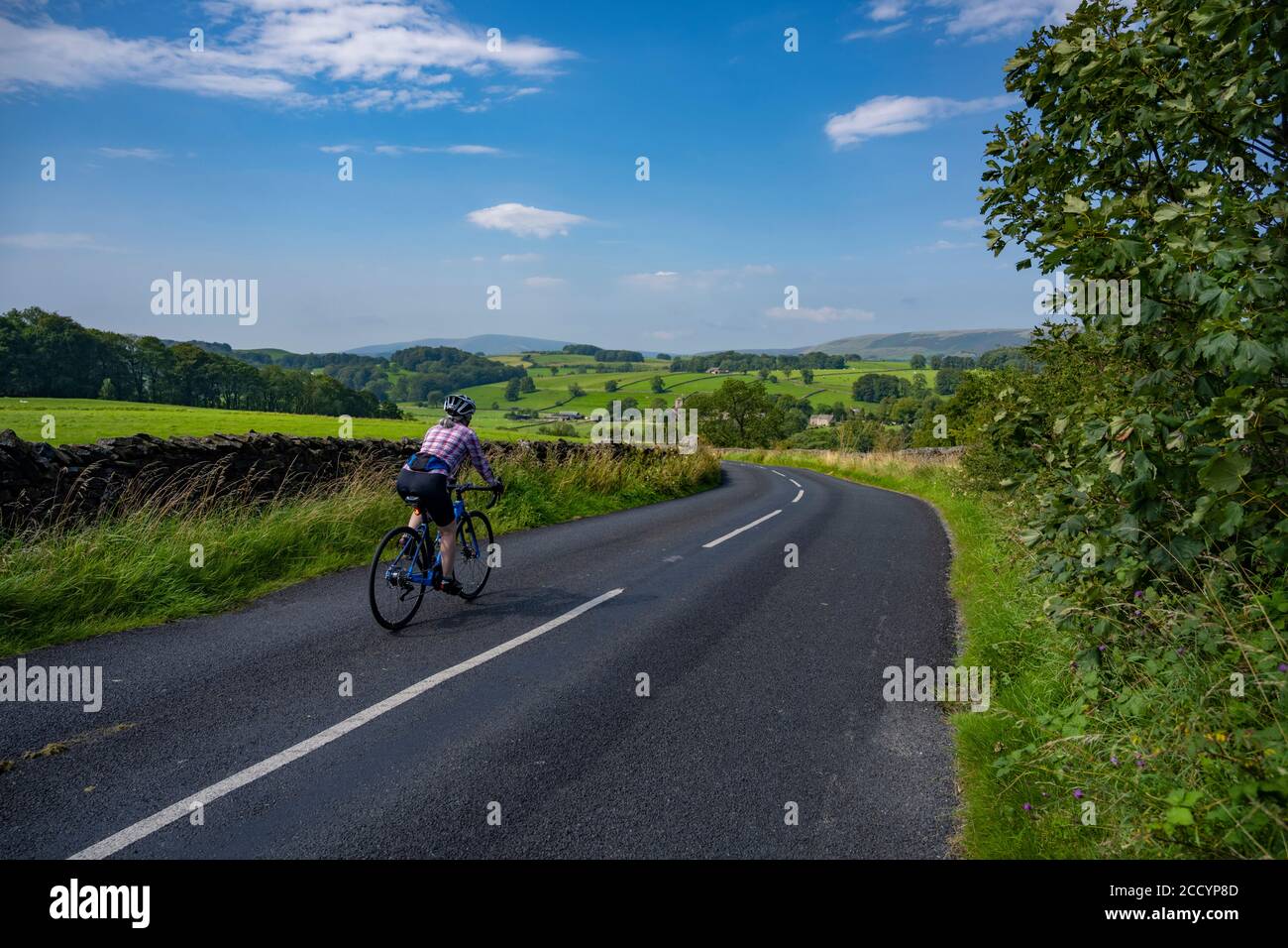 Cycliste femelle descendant dans le village de Slaidburn, dans le Lancashire, Bowland, Royaume-Uni. Banque D'Images