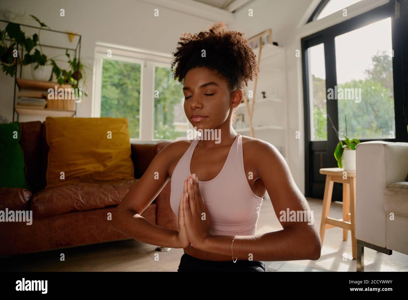 Portrait d'une jeune femme africaine aux yeux fermés pratiquant le yoga avec les mains des articulations Banque D'Images