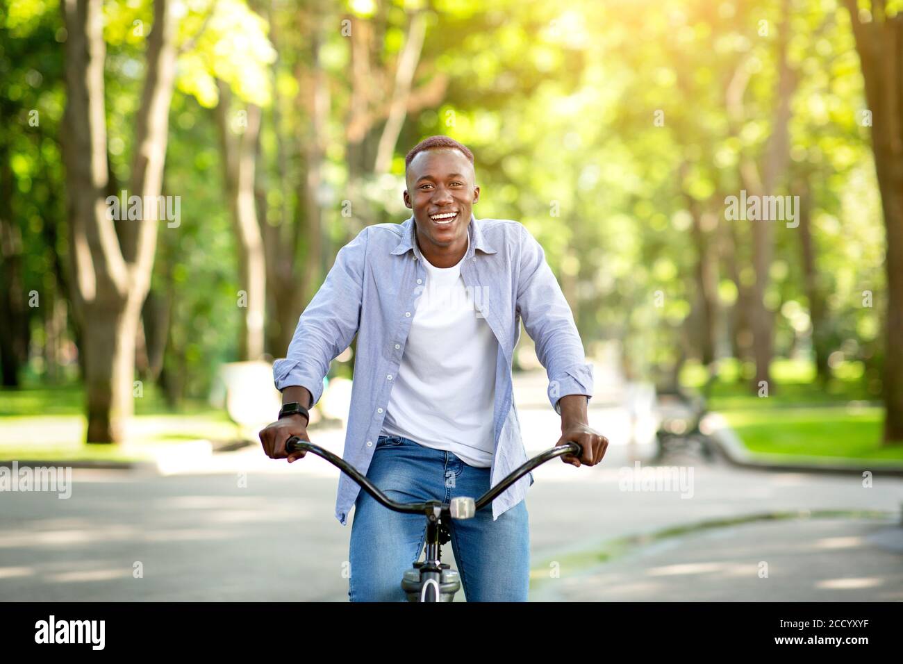 Un homme noir souriant appréciant sa promenade en vélo au parc l'été Photo  Stock - Alamy
