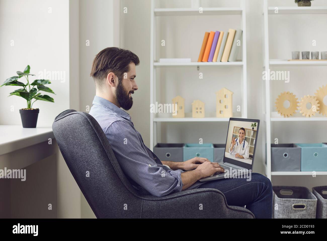 Concept de télémédecine. Jeune homme assis à la maison dans une chaise et parlant à un médecin en ligne. Banque D'Images