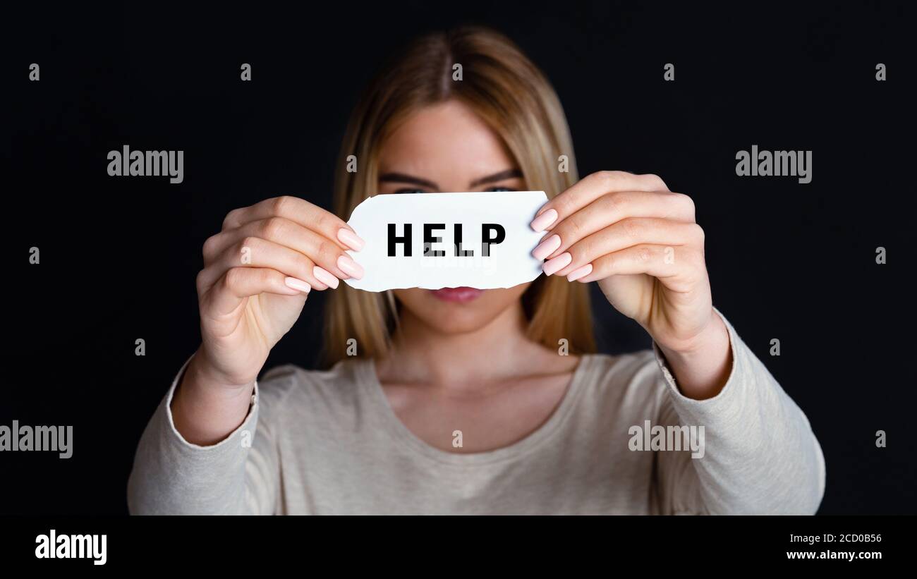 Appelez pour obtenir de l'aide. Femme méconnue tenant un morceau de papier avec inscription Banque D'Images