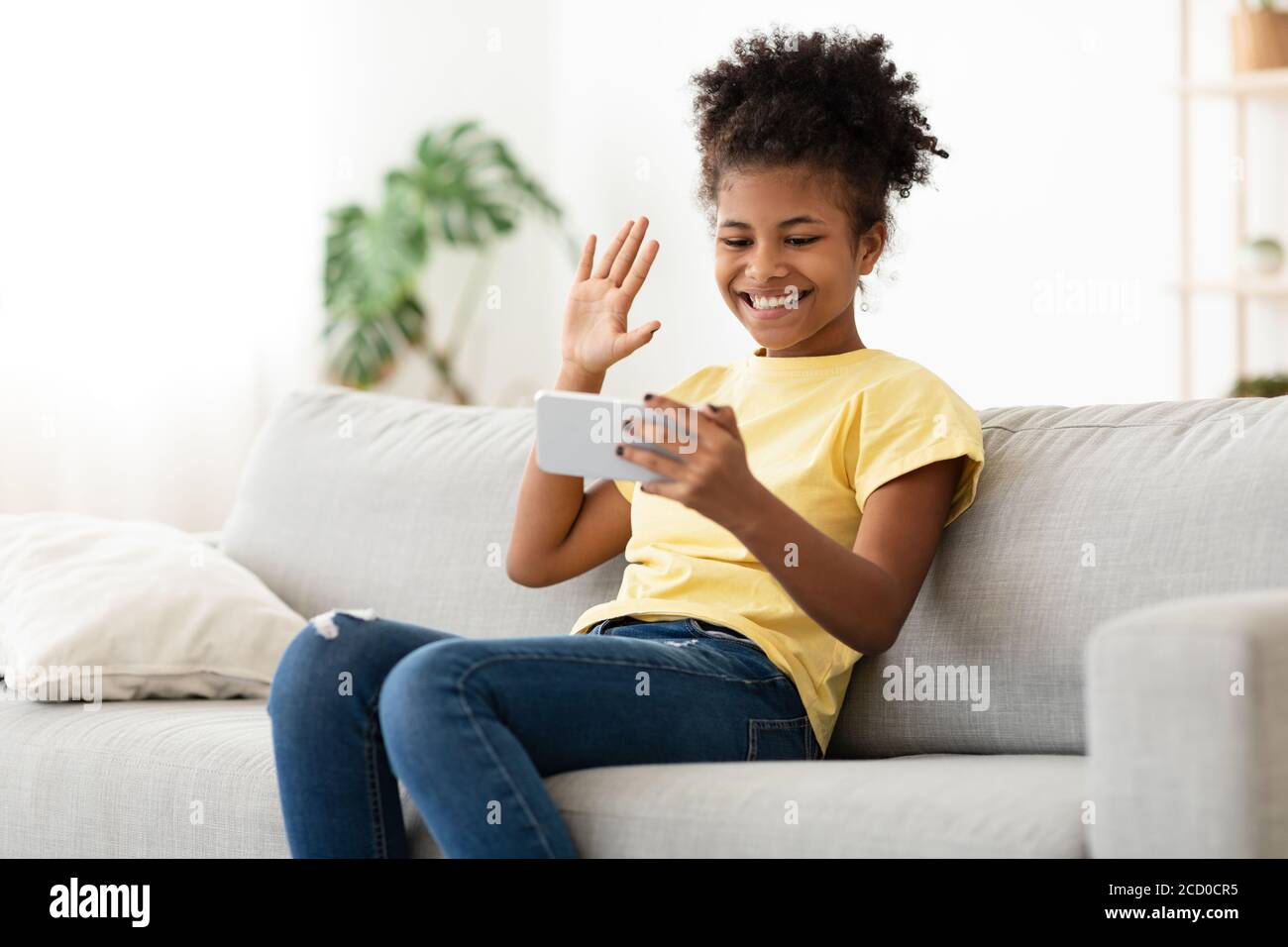 African Teen Girl avec smartphone passer un appel vidéo à la maison Banque D'Images