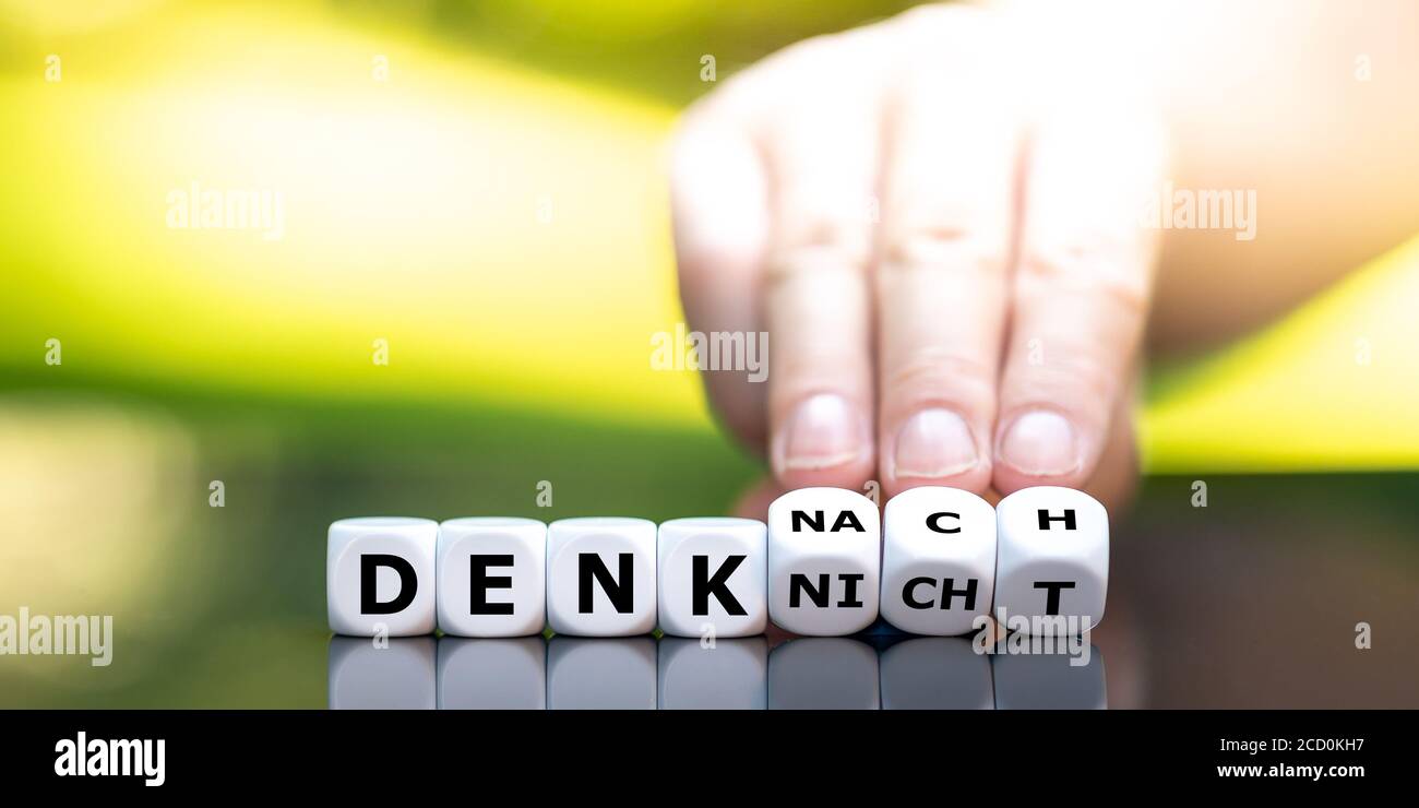 La main tourne les dés et change l'expression allemande 'denk nicht' (ne pense pas) en 'denk nach' (pense). Banque D'Images