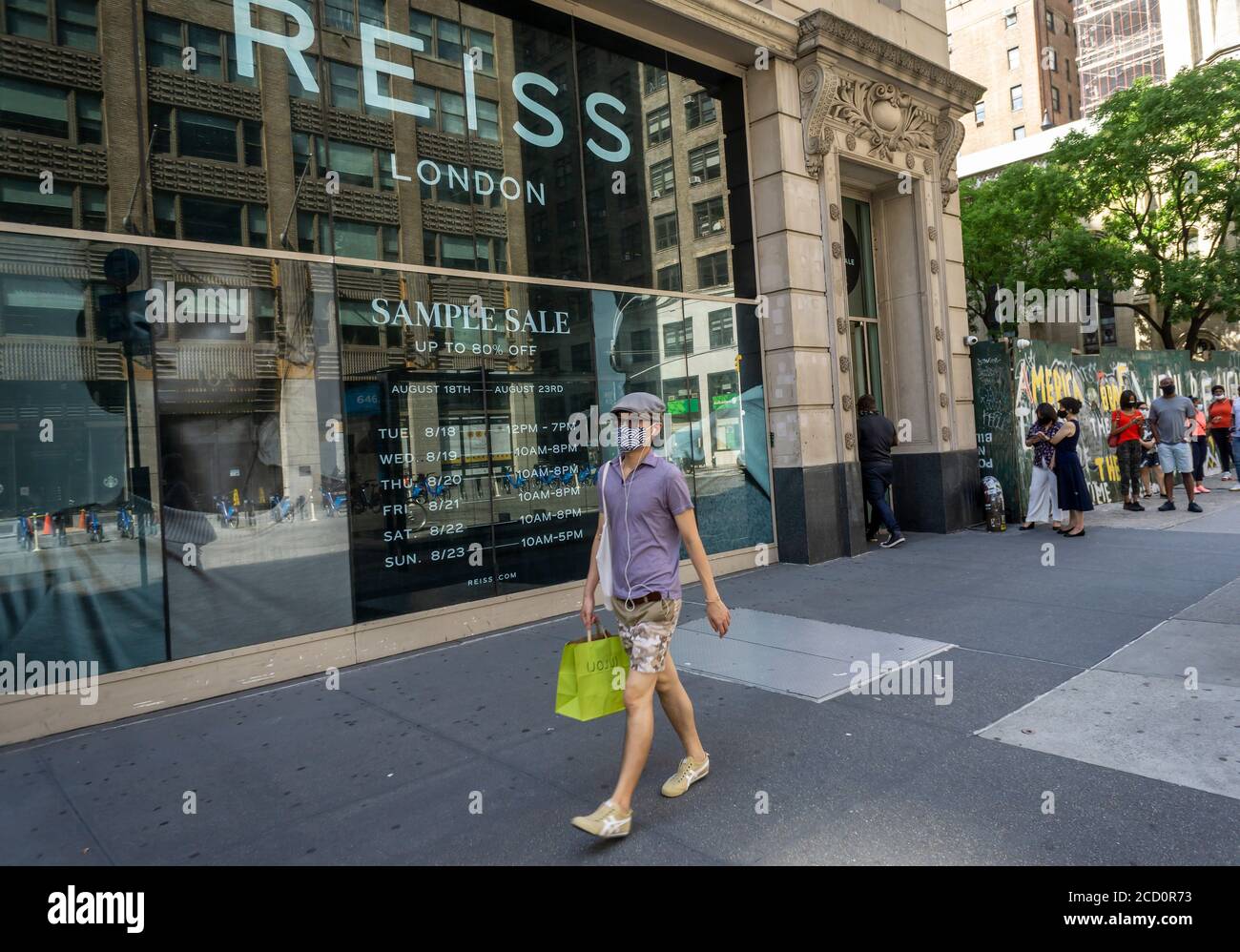 Les acheteurs avertis font la queue devant le magasin de vente  d'échantillons 260 à New York le mardi 18 août 2020 pour acheter des  vêtements et accessoires Reiss de créateurs très réduits. (©