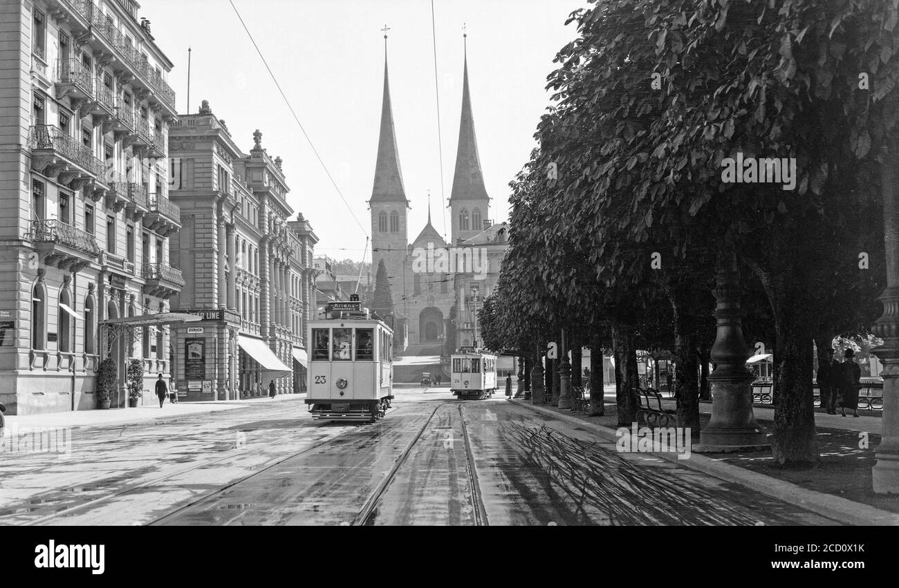 Photographie d'époque en noir et blanc des années 1920, en direction de la cathédrale de Lucerne, en Suisse. Vous pourrez voir des tramways électriques en bas de la rue. Banque D'Images