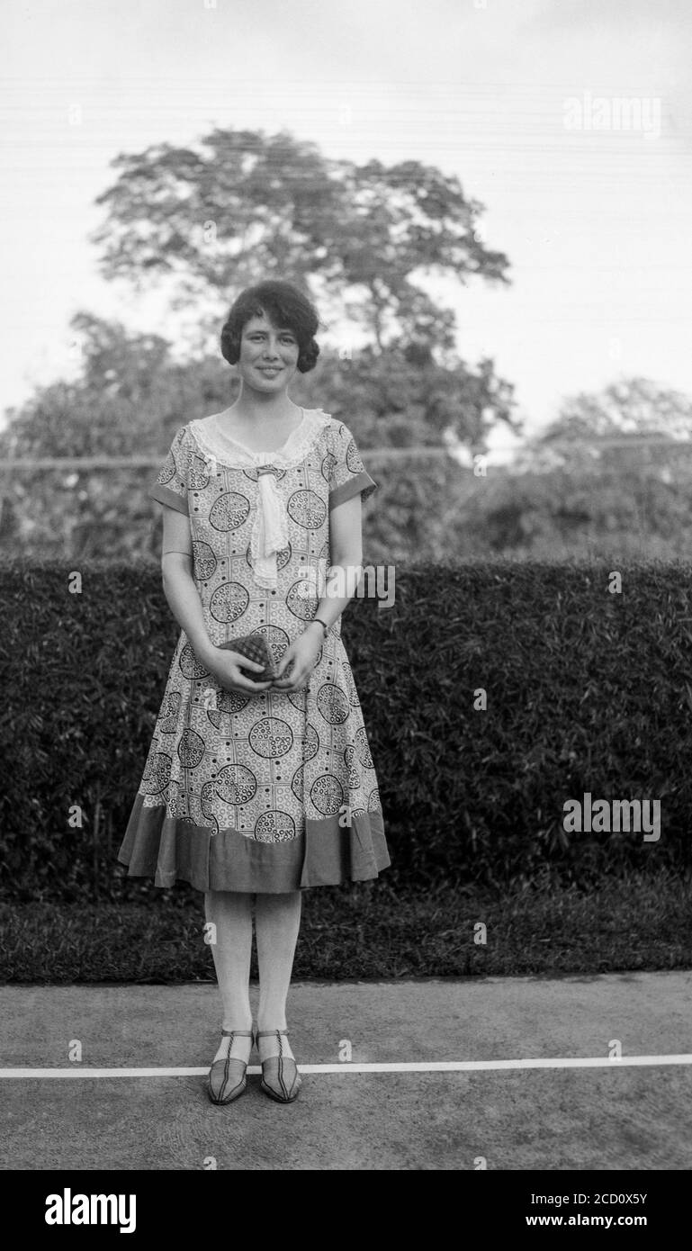 Photographie anglaise vintage des années 1920 en noir et blanc montrant une jeune femme, à l'extérieur, posant dans des vêtements à la mode de l'époque. Banque D'Images