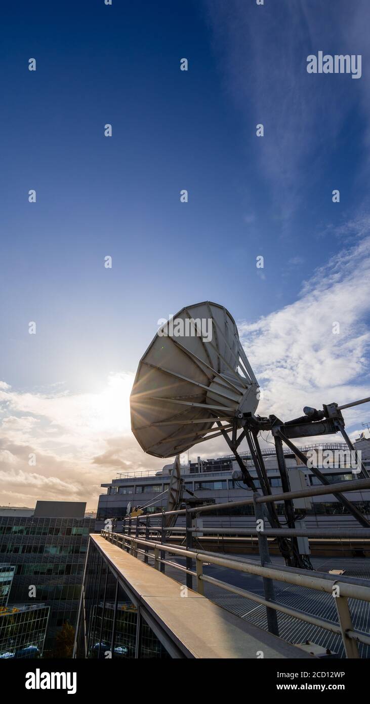 Plat satellite sur un bâtiment de bureau moderne, ciel bleu et coucher de soleil. Concept de communication longue distance Banque D'Images