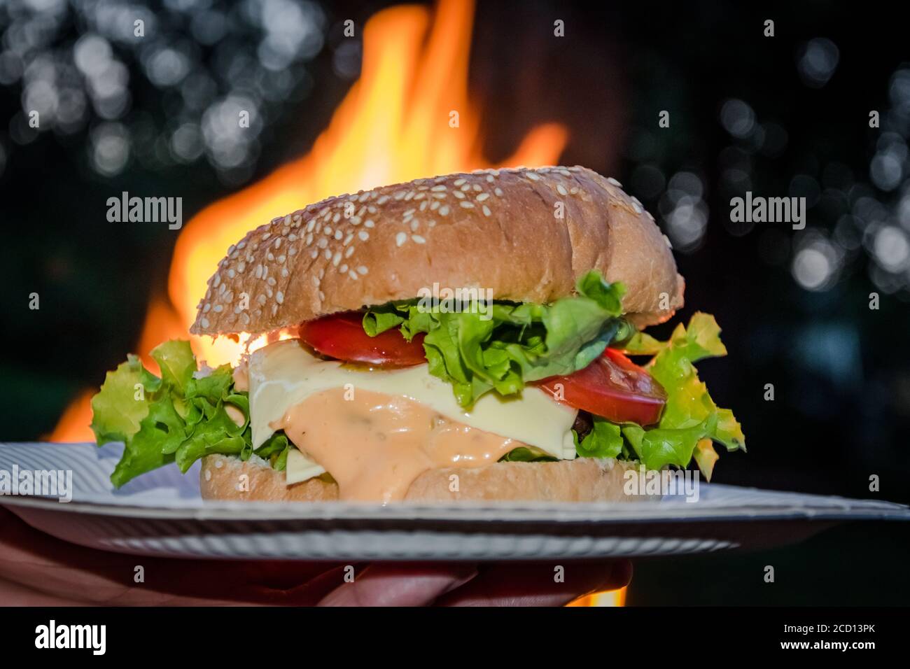 Hamburger classique savoureux et malsain devant la flamme du feu. Prenez le poids de la nourriture de rue et de restauration rapide. Banque D'Images