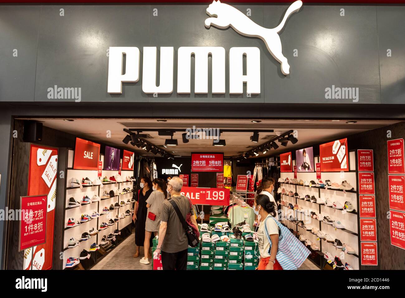 Des piétons portant des masques de visage marchent à côté de la marque multinationale allemande de vêtements de sport Puma magasin à Hong Kong. Banque D'Images