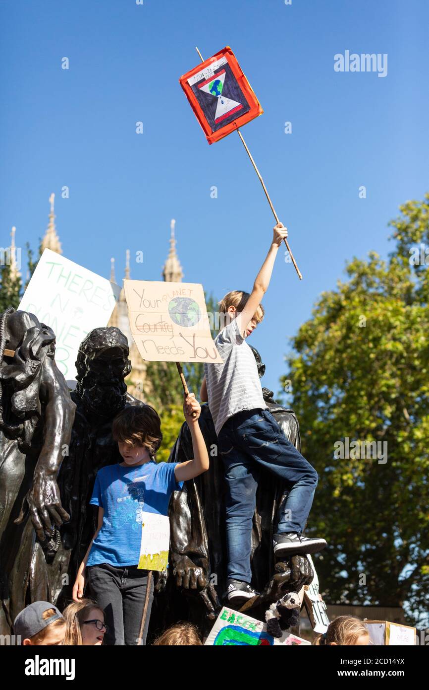 Un jeune garçon escaladant une sculpture en plein air et tenant un panneau de protestation lors de la grève climatique, Londres, 20 septembre 2019 Banque D'Images