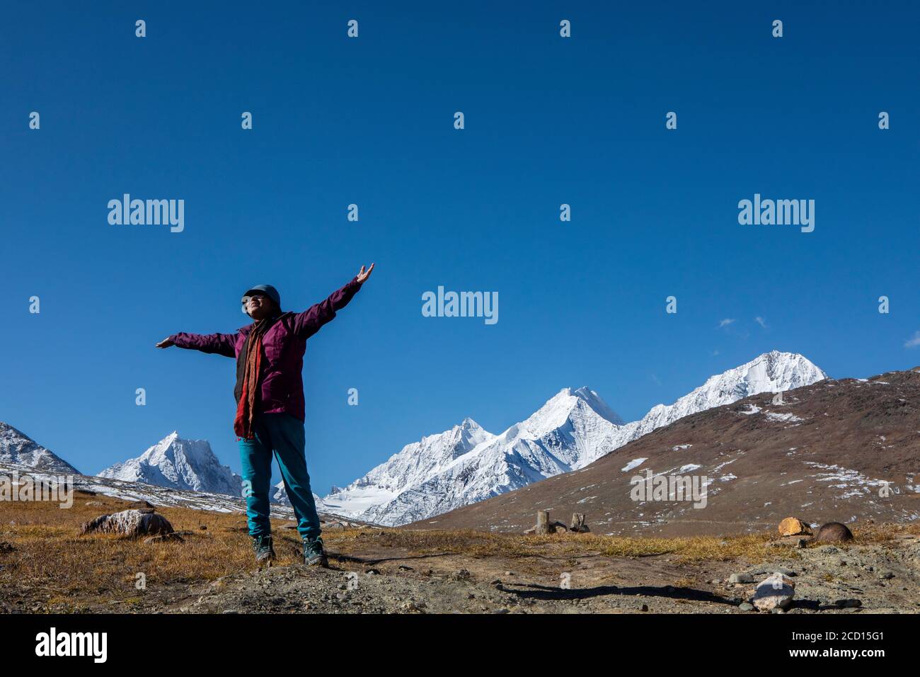 Une jeune femme avec une veste rouge sur le dessus de Kunzum Pass devant les sommets enneigés de l'Himalaya En Inde Banque D'Images