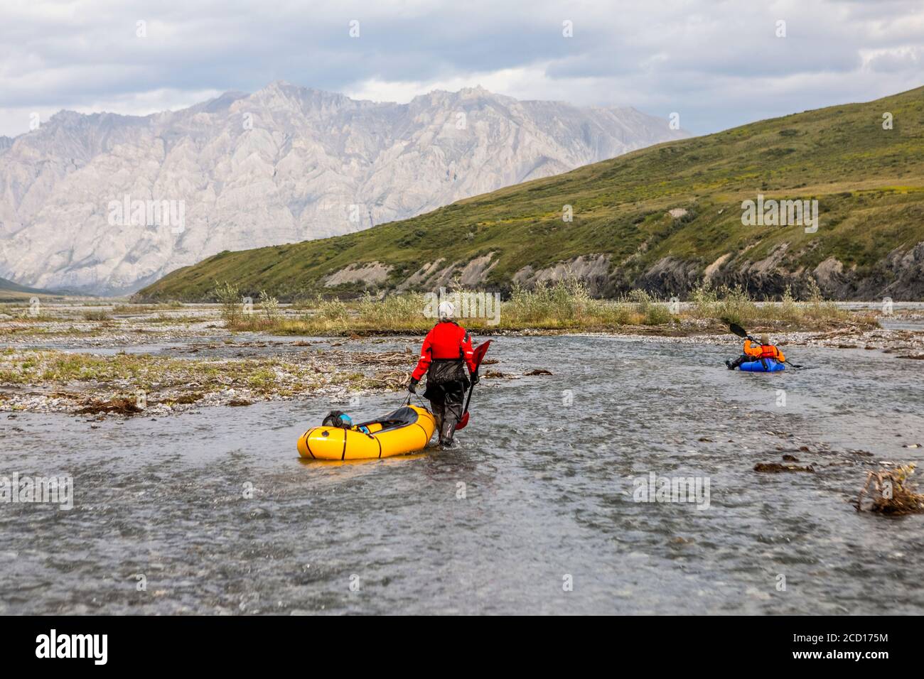 Une femme caucasienne portant une combinaison sèche rouge, tire son embarcation jaune vers le bas d'une tresse peu profonde de la rivière Marsh Fork, tandis qu'un homme caucasien portant un... Banque D'Images