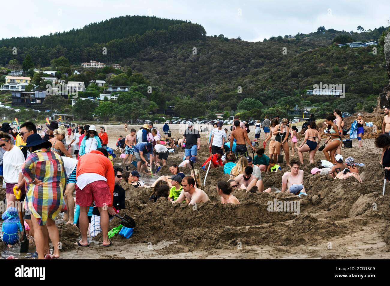 Les touristes qui creusent dans le sable à Hot Water Beach.Une rivière souterraine d'eau chaude coule de l'intérieur de la terre à la surface dans l'océan Pacifique... Banque D'Images