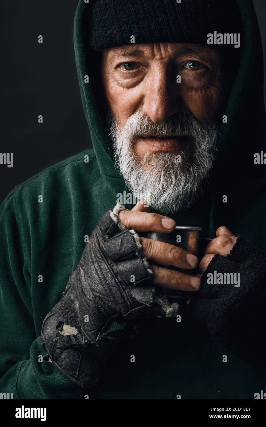Vieux sans-abri avec barbe grise couvrant en vert une tenue décrépite  tenant une tasse de thé chaud au chaud lui-même dans une nuit froide Photo  Stock - Alamy