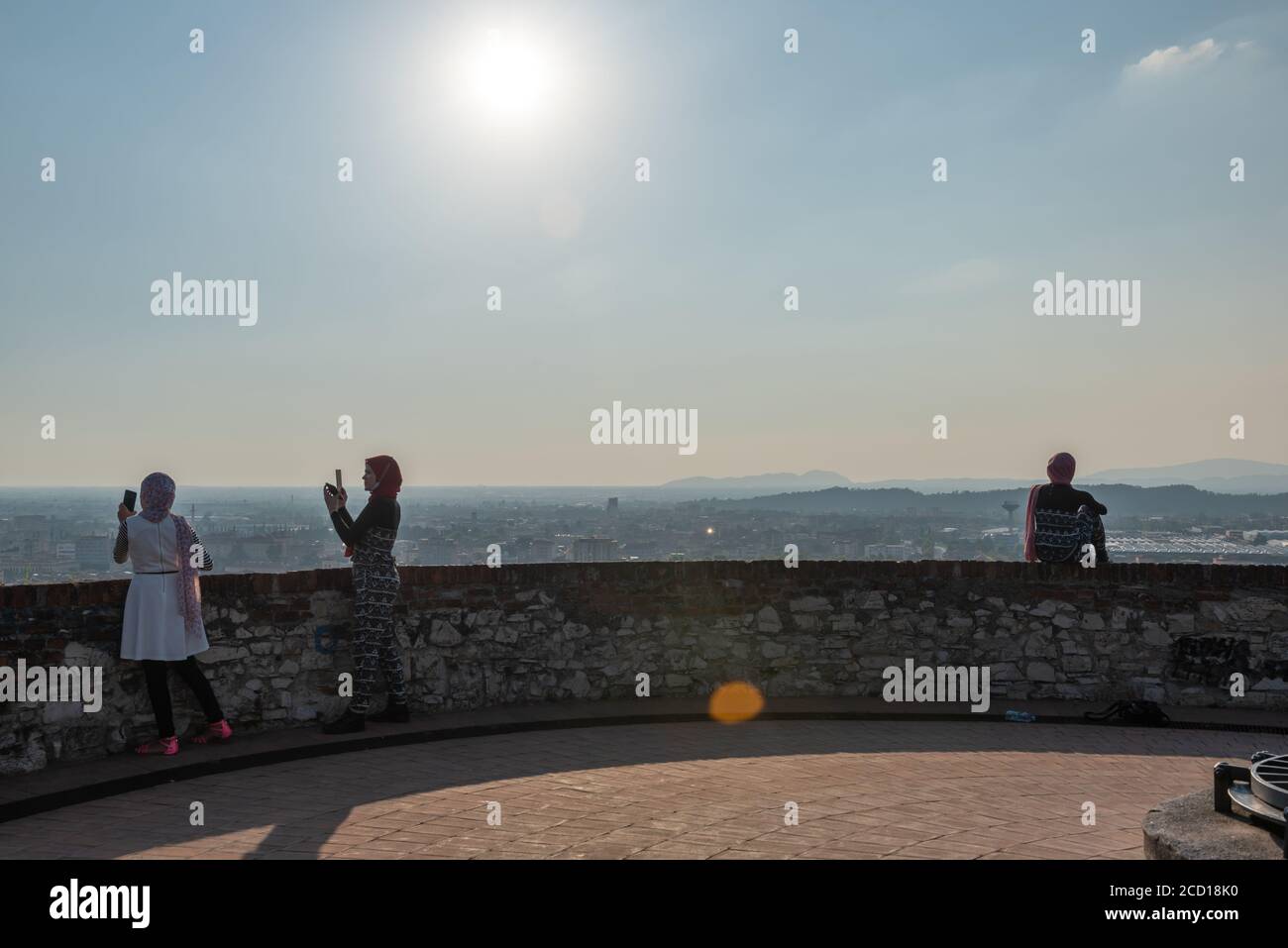 Egyptiennes avec smartphon sur le toit-terrasse avec vue aérienne de la vieille ville italienne de Brescia. Banque D'Images