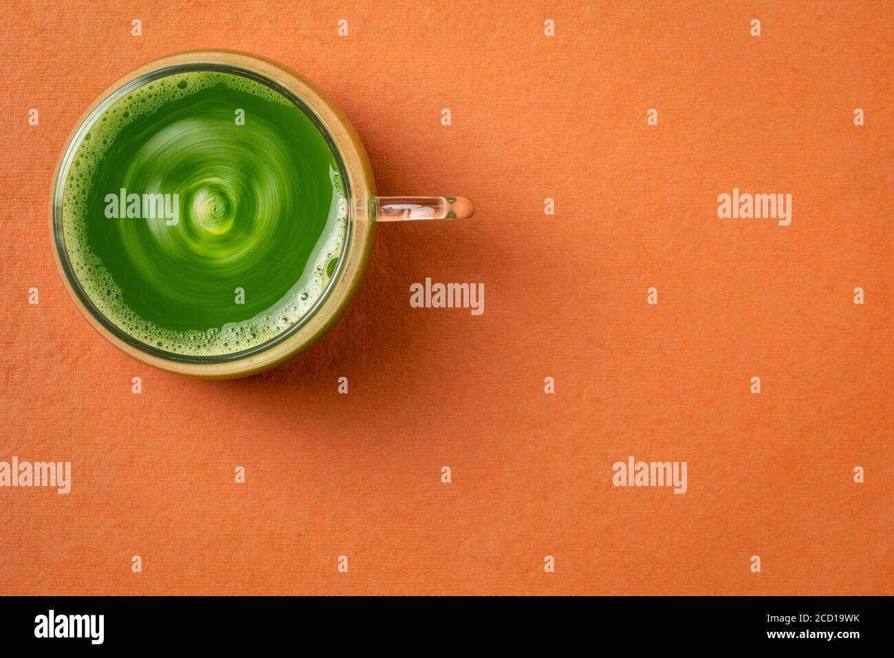 une tasse de verre de jus de concombre frais fait maison sur fond de papier orange avec un espace de copie, concept de saine alimentation Banque D'Images