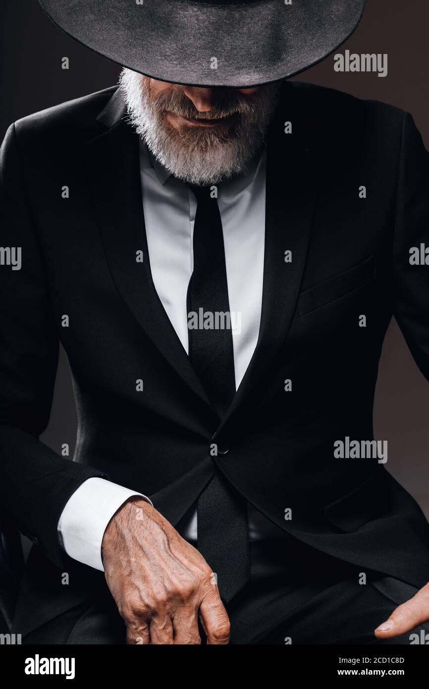 Homme barbu d'âge ancien, à l'image d'un agent secret anglais portant un  costume noir avec chapeau sur les yeux posé sur un fond sombre Photo Stock  - Alamy