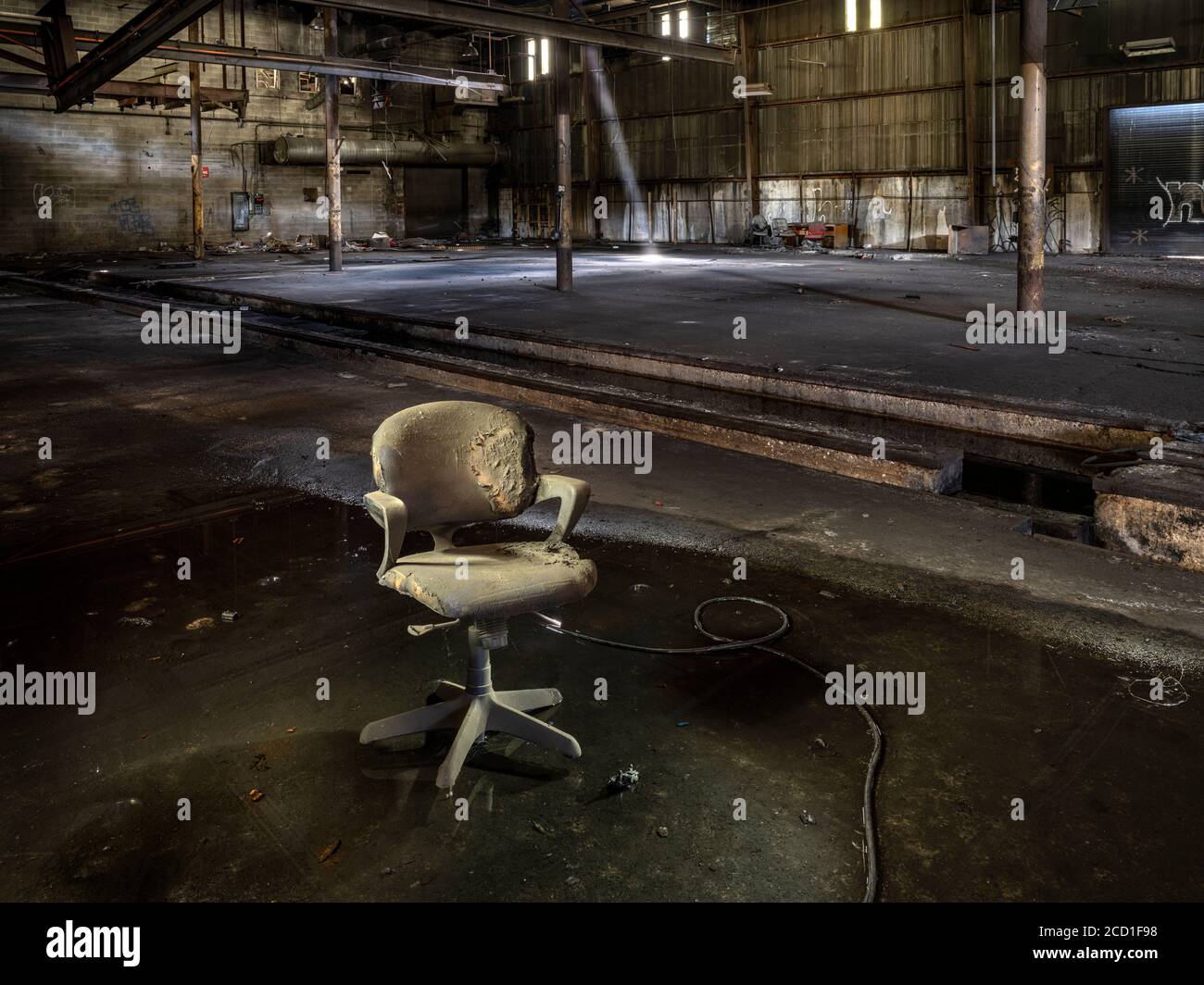 Ancienne chaise sale assise dans l'eau à l'intérieur d'une usine industrielle abandonnée Banque D'Images