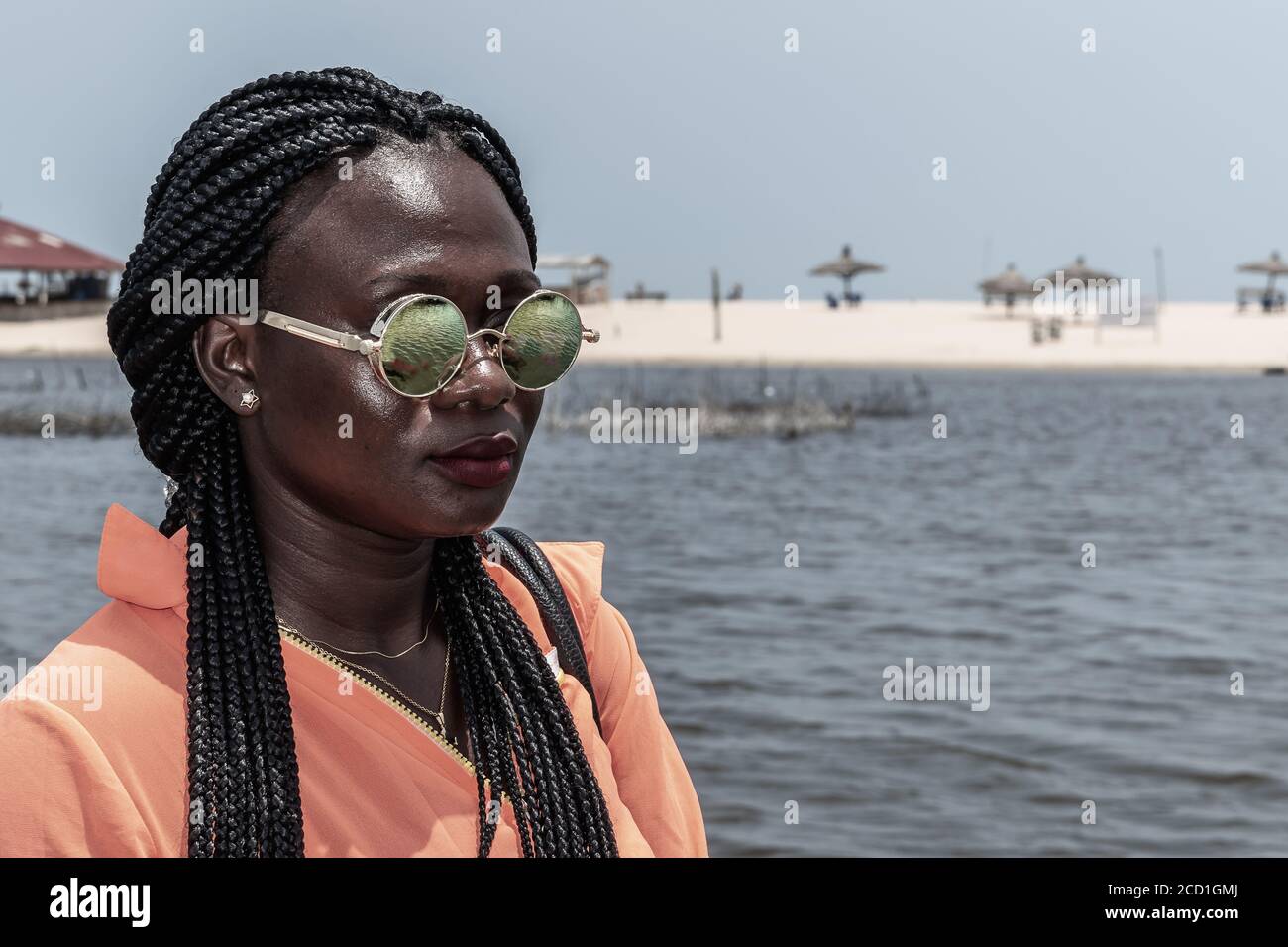 Femme africaine avec des lunettes de soleil du Ghana appréciant le soleil sur une plage à Accra. Banque D'Images