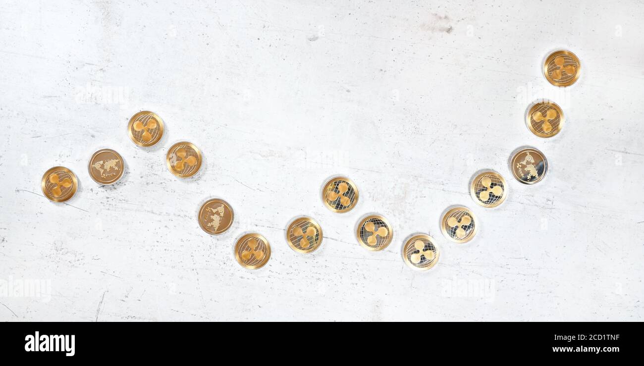 Vue de dessus, bureau en pierre blanche avec pièces ondulées dorées en forme de graphique ascendant - illustration du marché de crypto-monnaie XRP haussier Banque D'Images