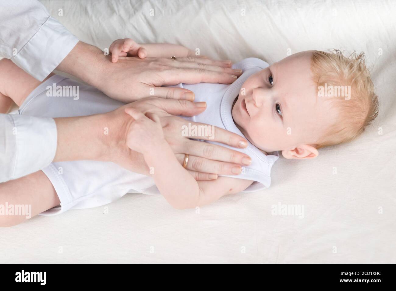 Les Femmes Massent Les Mains D Un Bebe Magnifique Dans Un Body Blanc Course Le Bebe Est Allonge Sur La Table A Langer Et Regarde Sa Mere Photo Stock Alamy