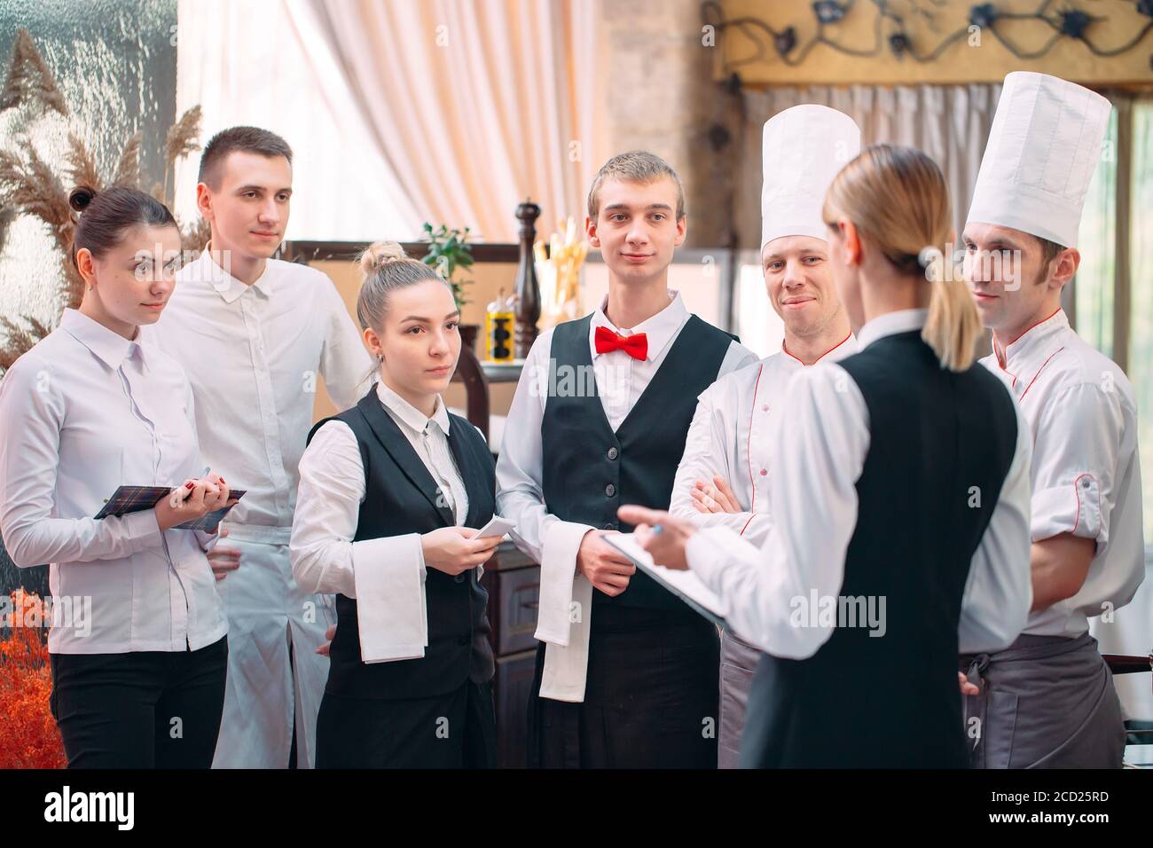 Gérant de restaurant et son personnel dans une cuisine. L'interaction de chef en cuisine commerciale. Banque D'Images