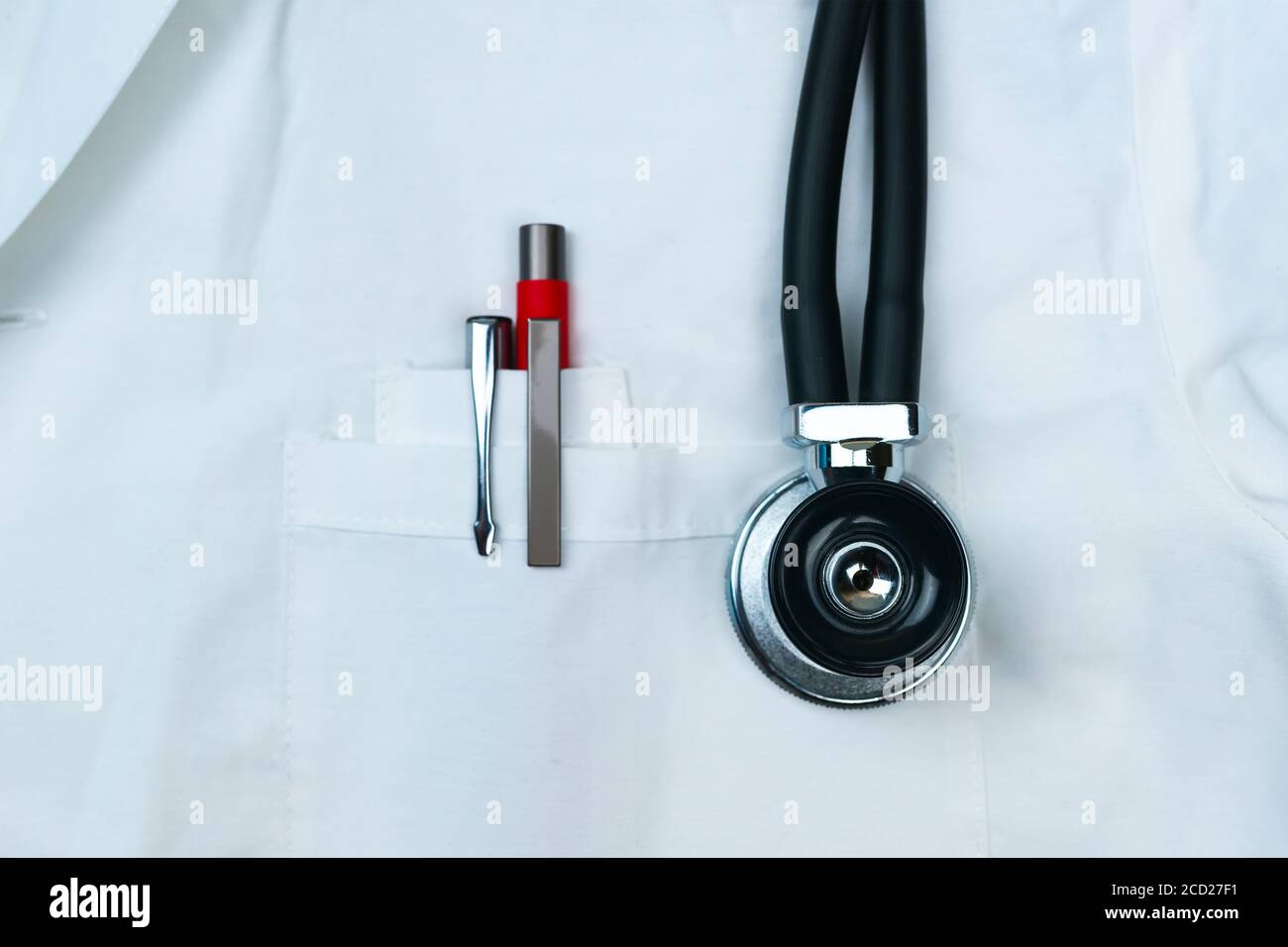 Stylos noirs et rouges dans la poche avant du manteau blanc du médecin avec stéthoscope phonendoscope gros plan. Mise au point Srrctive. Banque D'Images