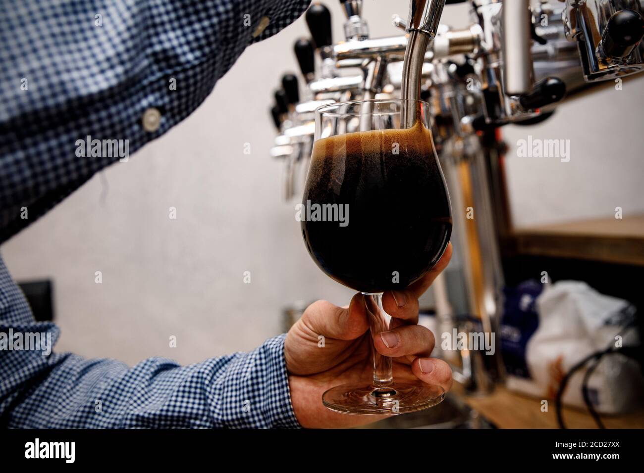 Le barman verse de la bière fraîche et foncée du robinet au pub. Banque D'Images