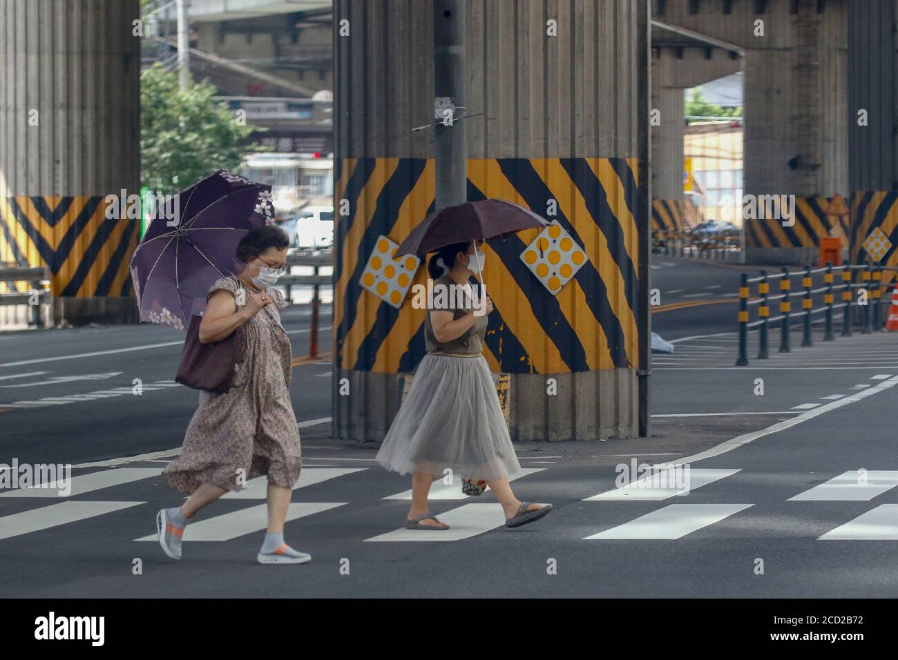 Séoul, KOR. 25 août 2020. 25 août 202-Séoul, Corée du Sud-A deux femmes ont croisé un masque avec une promenade au-delà de la passerelle à la jupe à Séoul, Corée du Sud. Le nombre de nouveaux cas quotidiens de coronavirus en Corée du Sud est resté inférieur à 300 pour la deuxième journée consécutive mardi, mais les autorités sanitaires ont averti que le pays était au bord d'une pandémie nationale en raison de la poursuite de la transmission du virus lié à l'église et d'un nombre croissant de patients présentant des voies d'infection inconnues. Le pays a signalé 280 nouveaux cas de COVID-19, dont 264 infections locales, ce qui porte le nombre total de cas à 17,945, selon le Kor Banque D'Images