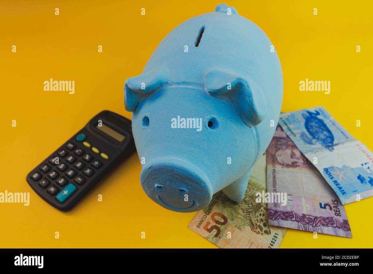 Pièces de monnaie piggy avec calculatrice et argent brésilien isolé. Banque D'Images