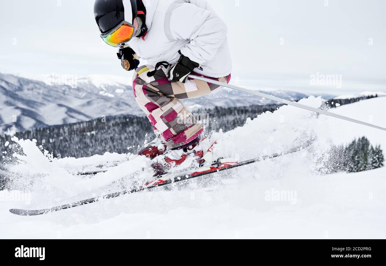 Skieur mâle skier sur de la neige poudreuse fraîche avec de belles montagnes d'hiver en arrière-plan. Homme freerider faire sauter tout en glissant sur des pentes enneigées. Concept de sports d'hiver et station de ski. Banque D'Images