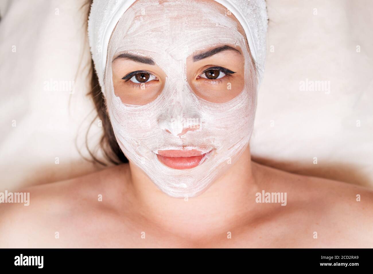 Une femme se trouve avec un masque cosmétique appliqué sur son visage. Plan de cronym de portrait. La vue du dessus. Concept de soins de la peau et de la cosmétologie. Banque D'Images