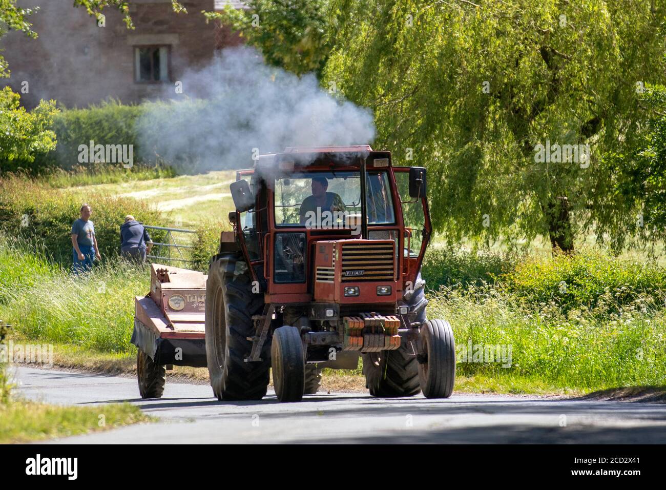 Ancien tracteur Fiat Trattori roulant sur des routes rurales avec des émissions de fumée et une remorque, Manchester, Royaume-Uni Banque D'Images