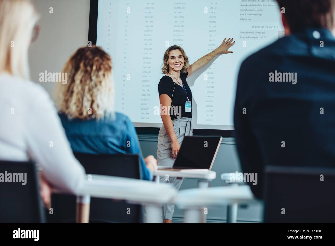 femme d'affaires offrant une présentation tout en pointant vers l'écran regardant des collègues et souriant. Femme cadre donnant une présentation informative Banque D'Images