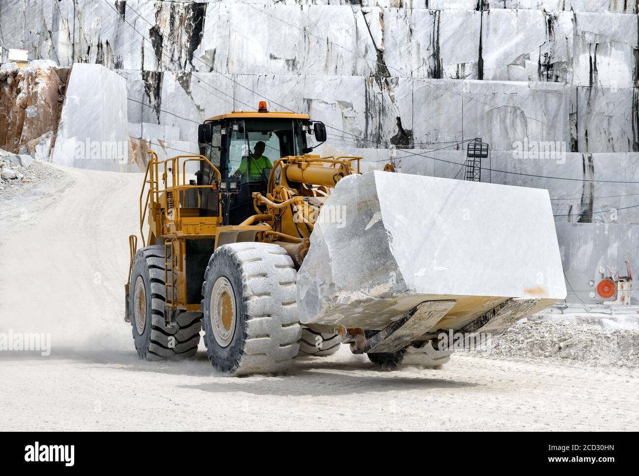 Chargeur frontal extra-robuste déplaçant un grand bloc de marbre de Carrare blanc dans une mine ou une carrière en fonte ouverte en Toscane, Italie Banque D'Images