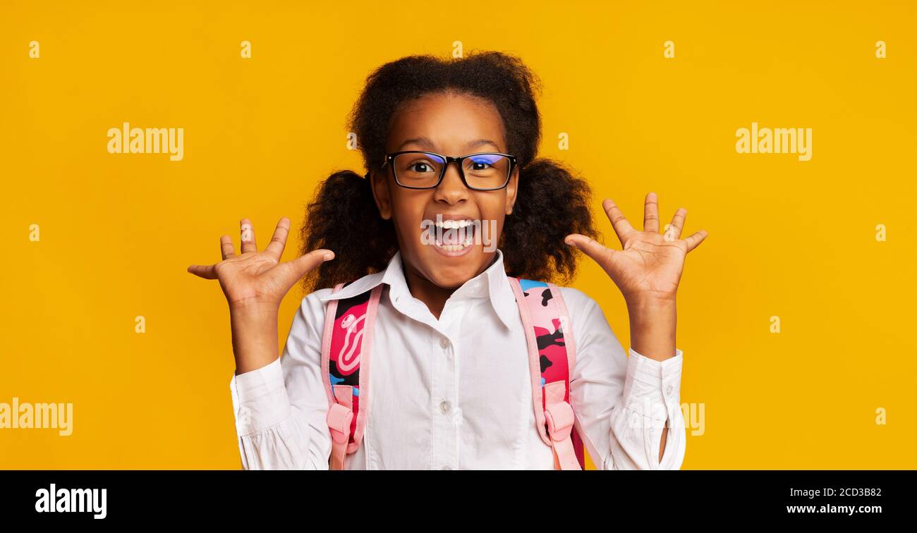 Écolière noire criant dans l'excitation posant sur fond jaune, Panorama Banque D'Images