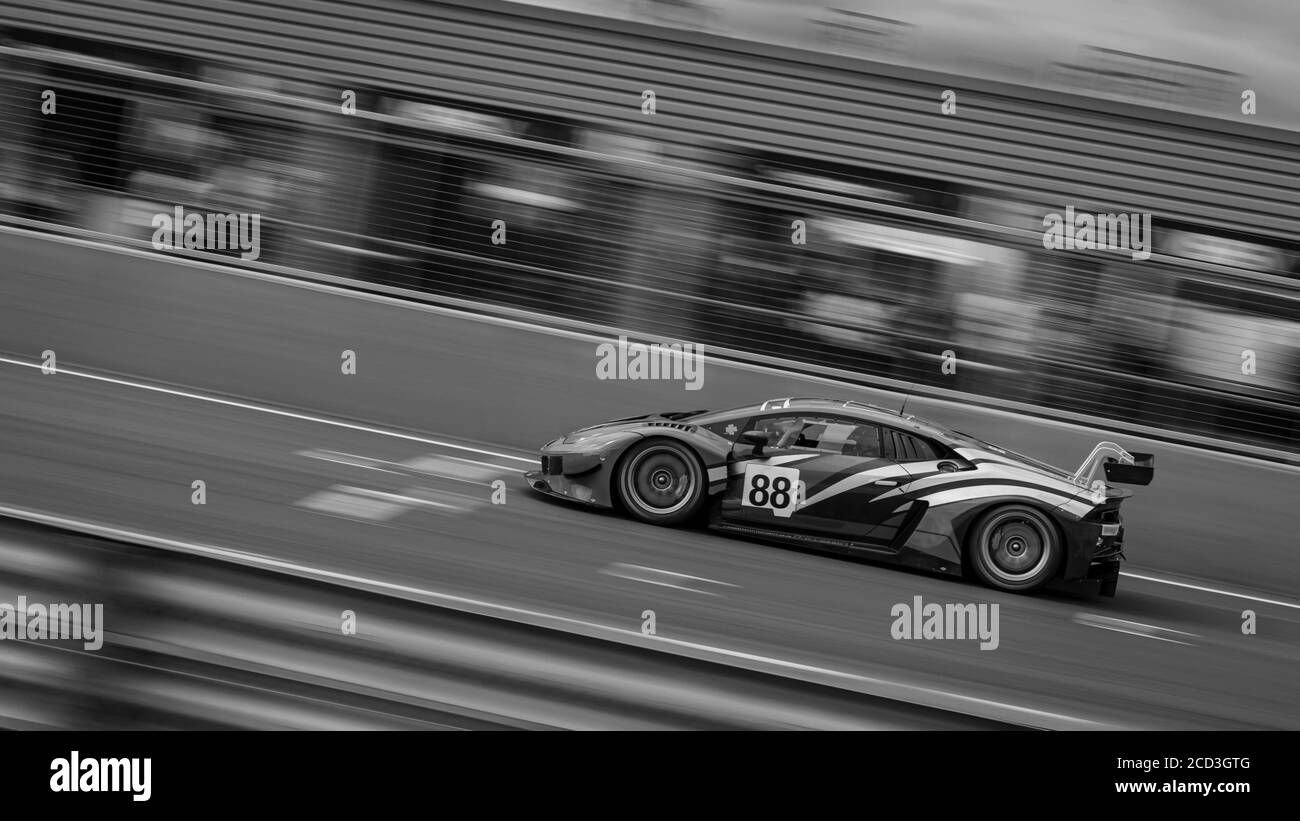 Un panoramique monochrome d'une voiture de course lorsqu'elle fait le circuit d'une piste. Banque D'Images