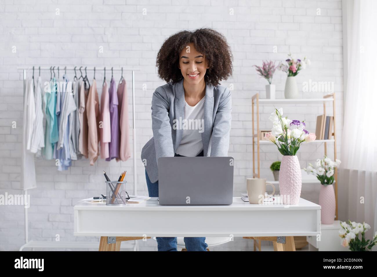 Démarrage à domicile. Femme afro-américaine souriante travaillant avec un ordinateur portable en studio Banque D'Images